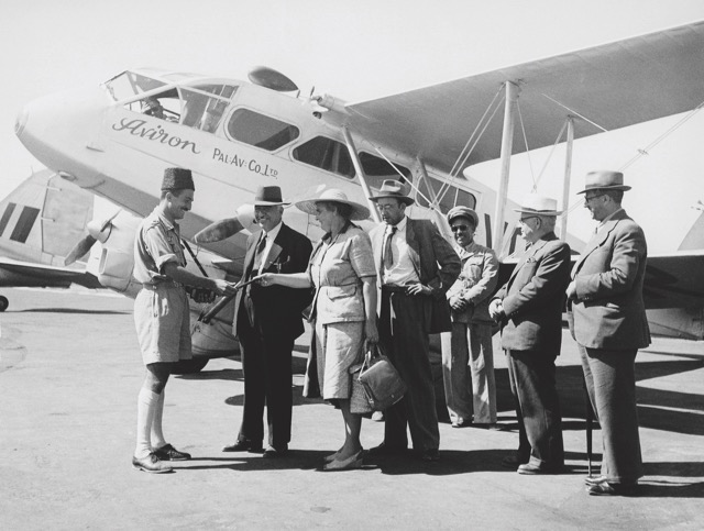Inspecting passenger documents for an Aviron flight from Lydda on 25 October 1947 with Dragon Rapide VQ-PAR. In the background at left is the tail of a Royal Air Force Douglas C-47 Dakota. The female passenger is Rachel Cohen, then with the Va’ad Le’Ummi (the governing council of the Jewish settlement in Palestine) and later a member of the first elected Knesset, the legislative body of the State of Israel. (Israel Government Press Office) 
