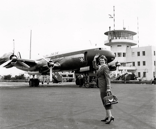 EL AL's first Israeli flight attendant, Miriam Gold, waves in front of an EL AL Constellation at Lod Airport, 1951. Her flight bag is probably EL AL's earliest one.