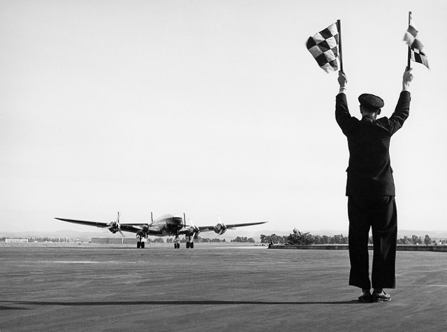 First arrival of an EL AL Constellation (4X-AKB) at Lod Airport, on 22 December 1950, commanded by Capt Sam Lewis with Leo Gardner as first officer. Hillel Simon, operations officer at Lod, guides the aircraft in with upraised flags. (Israeli Government Press Office, Teddy Brauner photo) 