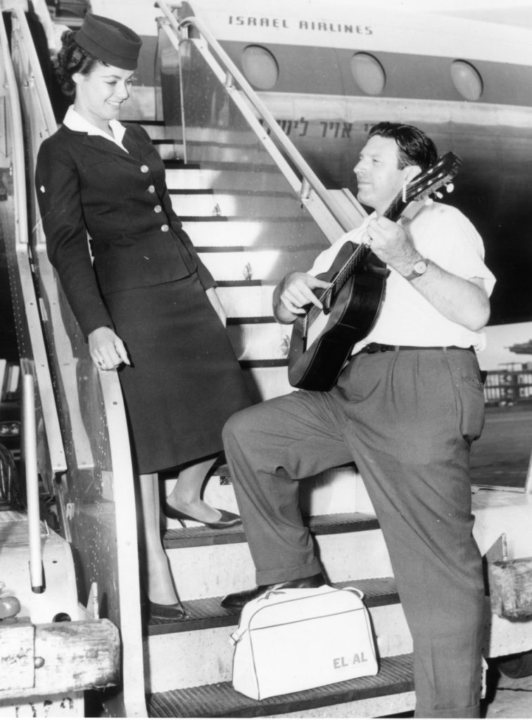 Singer and actor Theodore Bikel serenades EL AL ground hostess Yolan Soloman prior to boarding a Britannia in New York. (EL AL Archive) 
