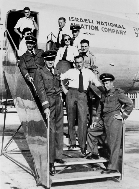 Some of the crew members of the Weizmann flight on steps leading to 4X-ACA at Ekron Air Base, Israel, about 26 September 1948. Left side, top to bottom: Yehuda Shimoni (navigator); Leah Melamed (assistant to Aharon Remez of the Israeli Air Force); Milt Shatan [Louis Neigle?] (flight engineer); Arnold Ilowite (co-captain). Right side, top to bottom: Yitzhak Hennenson (co-captain); Herb Bornstein (flight engineer) [Hal Auerbach?]; Leah Barbash (flight attendant); Ya’acov Feldman (Israel Defense Forces representative); Norbert Solomon (steward); Joe Segal (radio operator). The blue uniforms with gold trim were custom made for the flight by a Tel Aviv tailor. The hat insignia is a “Flying Camel”, reminiscent of the Jewish settlement's Flying Camel glider club of the 1930s and of a flying camel statue at an exposition hall in Tel Aviv. (State of Israel Ministry of Defence, Military (I.D.F.) & Defence Establishment Archives)