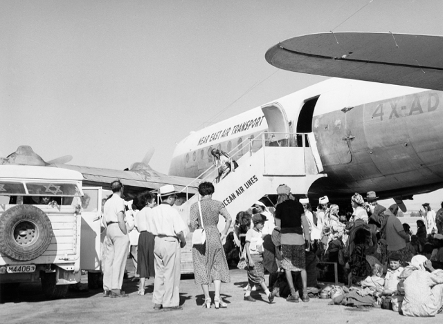 Habbanim Jews from the South Arabian Peninsula, airlifted from Aden, arrive at Lod Airport aboard EL AL's DC-4 4X-ADN on 26 August 1950. As EL AL could not fly airplanes in its own colors to many Middle Eastern points, liveries of associated charter airlines such as Near East Air Transport were usually used. Near East was funded in part by Israeli Jewish interests and commonly used EL AL crews. The stairs are marked Transocean Air Lines, a pioneering post-World War II US charter airline. (Israel Government Press Office, Fritz Cohen photo)