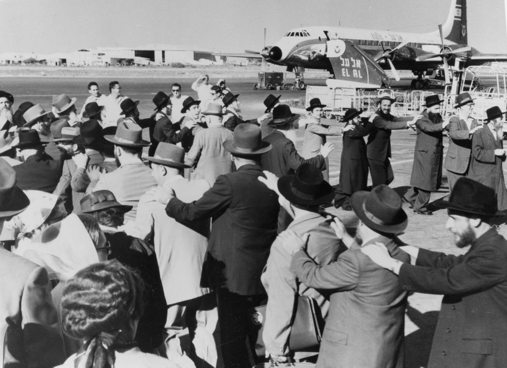 Orthodox Jews dancing around their rebbe (spiritual leader) to greet him upon arrival at Lod Airport, about 1958, with Britannia 4X-AGC in the background. (EL AL Archive)
